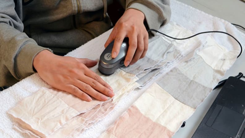 A tester uses a photospectrometer to measure stains on several washed stain strips.