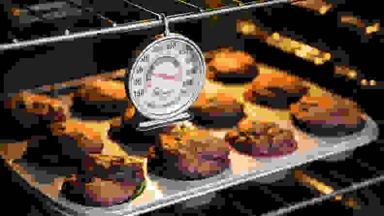 KT Thermo oven thermometer hangs inside an oven above baking muffins.