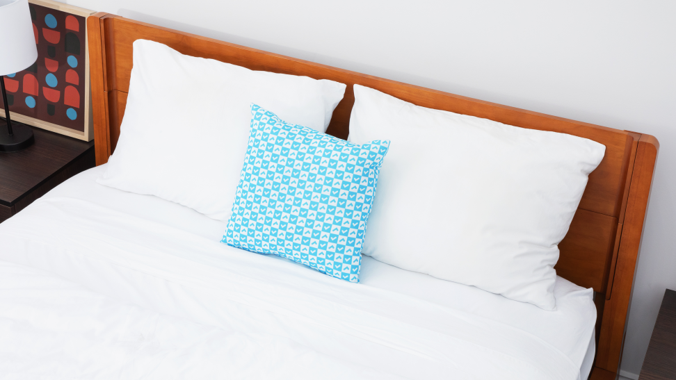 A bed with white sheets and a blue pillow