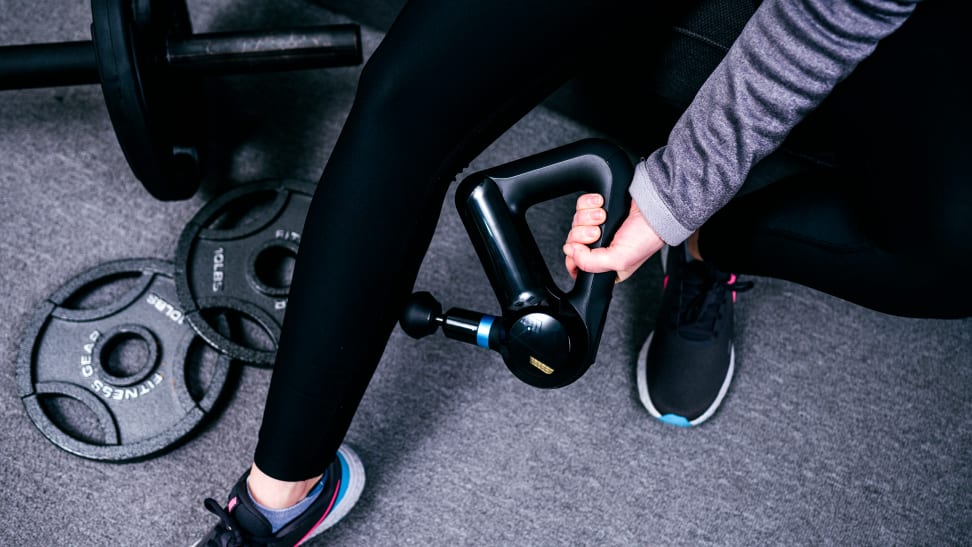 A woman using the Therabody Theragun Elite massage gun on her calf muscle.