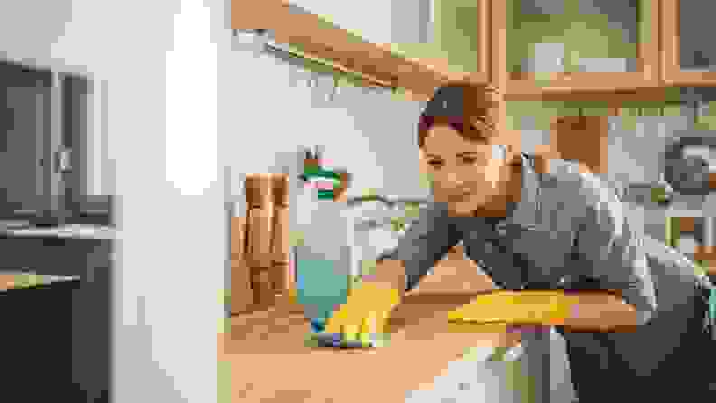 A woman wipes down a kitchen counter.