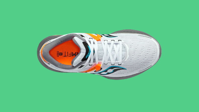 An orange and white sneaker against a green background.