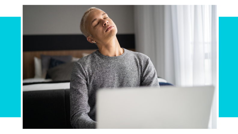 A person stretching their neck in front of their laptop.