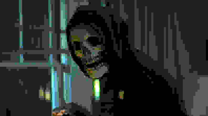 A person in a skeleton mask against a window, in a scene from