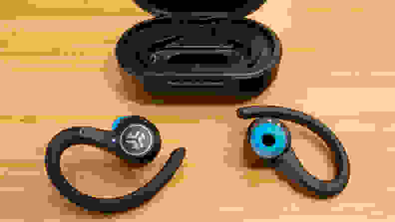 A pair of JLab Epic Air Sport earbuds and charging case on a brown table.