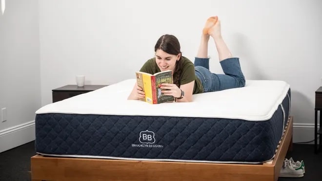 Brooklyn Bedding mattress with a woman on top in a bedroom setup