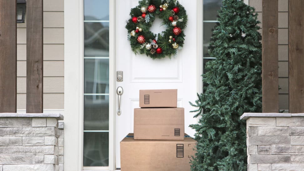 Stack of boxes sitting on a front porch decorated for the holidays.