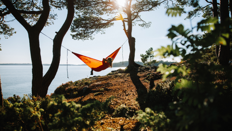 Person relaxing in hammock overlooking a waterside cliff