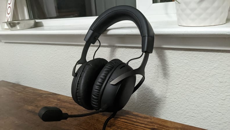 A black gaming headset on a tabletop leaning against a windowsill