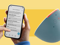 A person holding a smart phone next to an Alexa.