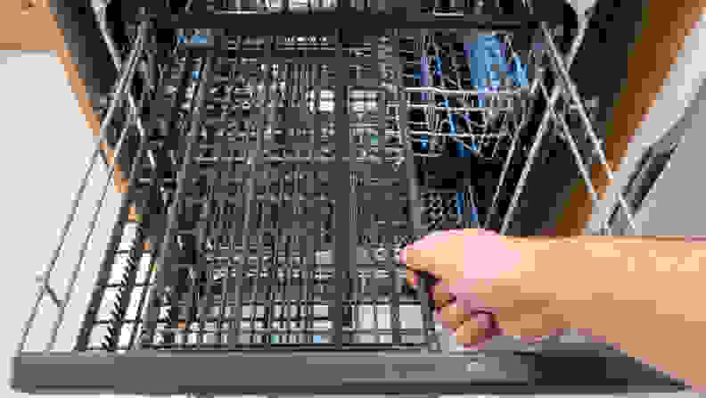 A close-up of a hand reaching into frame to slide the third rack's right half over to the left, opening up a lot of space for the rack underneath.