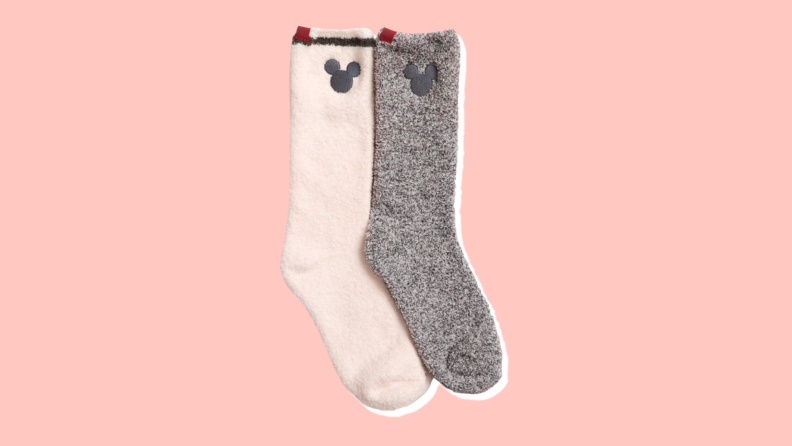 One white and one grey fuzzy crew socks with a stylized Mickey logo embroidered at the top.