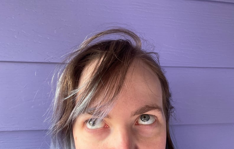 A person with messy hair on a purple background.