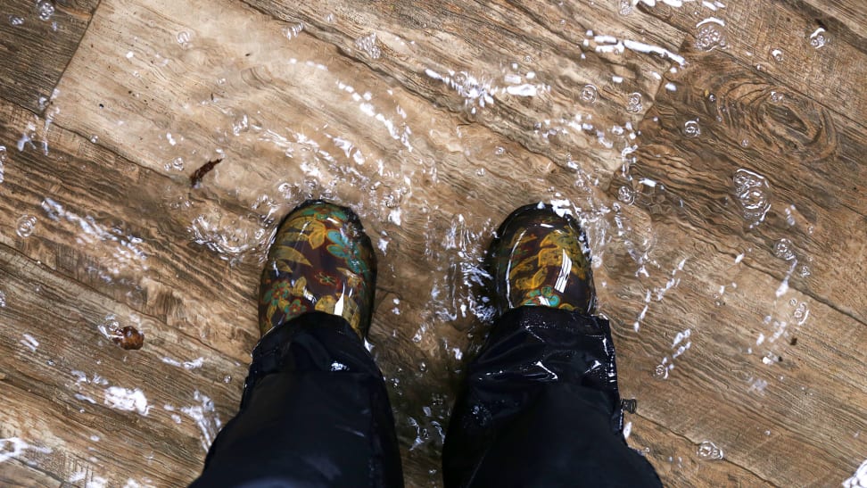 A top-down shot of someone's boots, standing on a flooded wood floor.
