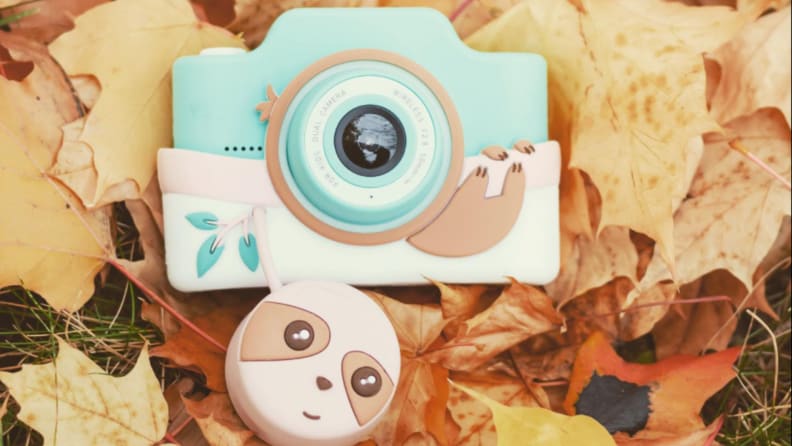 A blue Kidamento kids' digital camera on fall leaves.