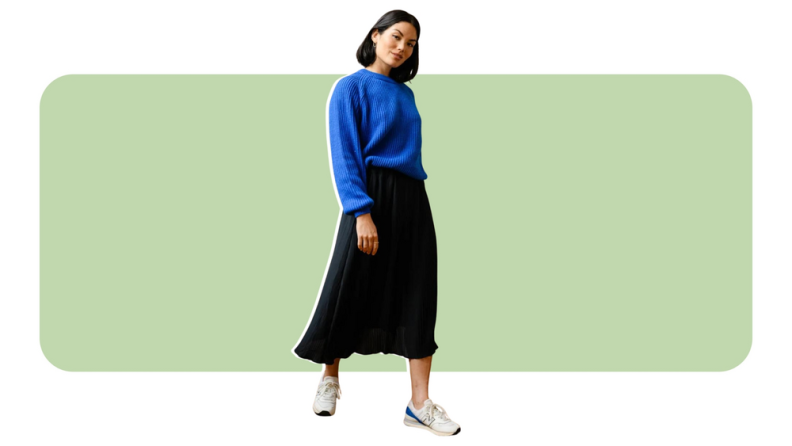 A model wearing a black pleated skirt with a blue sweater.
