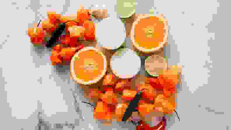 Oranges, peppers, and onions arranged artfully on a marble surface.