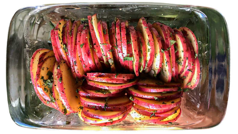 Thinly sliced potatoes arranged neatly in a glass baking dish.