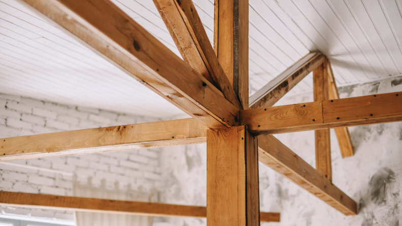 Photo of angular wooden rafters supporting a painted white ceiling.