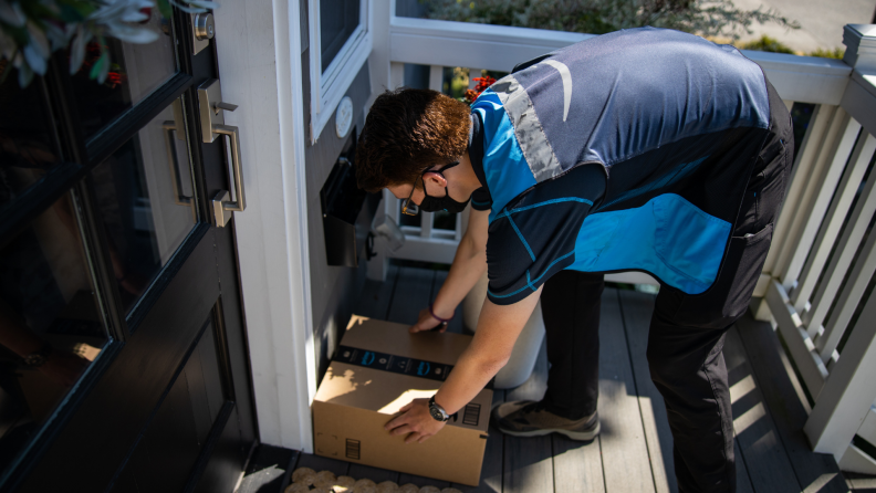 An Amazon delivery driver drops off a package at a front door.