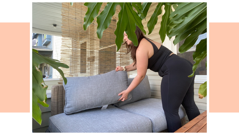 A person putting a pillow on their Outer Furniture set.