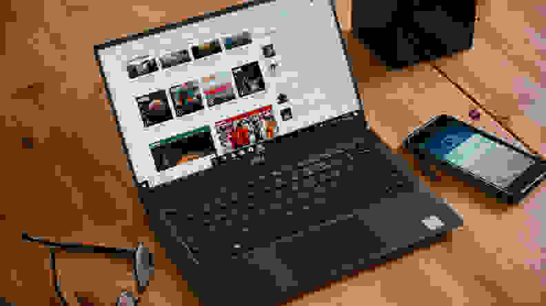 Laptop on desk surrounded by glasses and phone