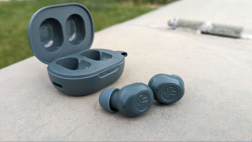 A pair of JLab JBuds Minis next to their case in an outdoor setting.