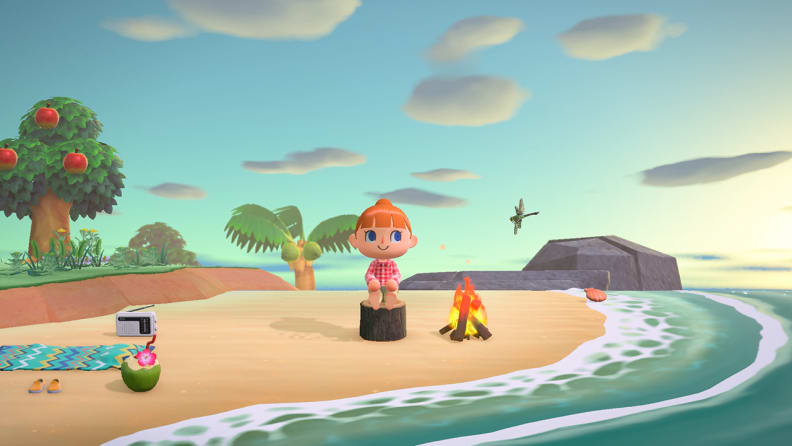 A red-haired girl sits on a tree stump at the beach, looking out toward the waves with a smile.