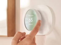 Person adjusting a smart thermostat on the wall.