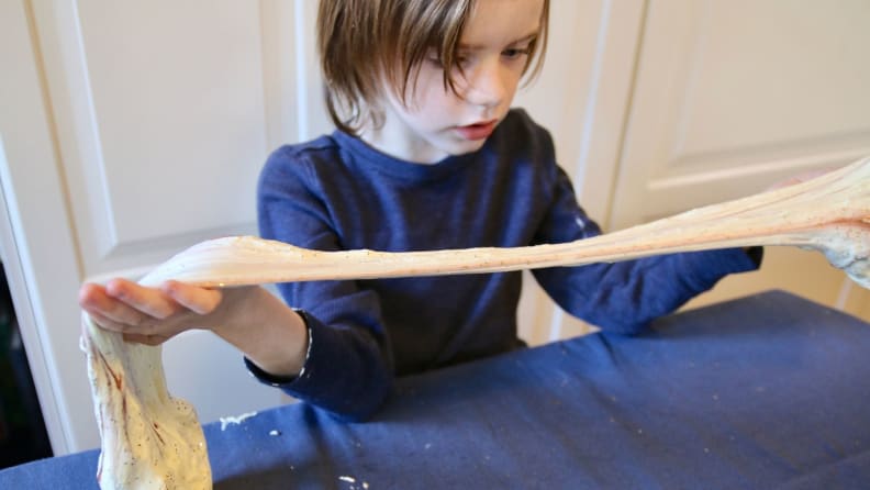 Little boy looking at slime stretching.
