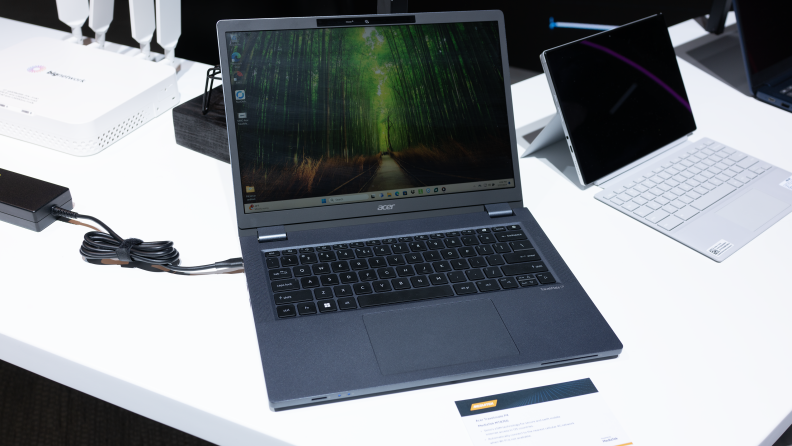 The Acer TravelMate P4 open on a table displaying a forest scene.