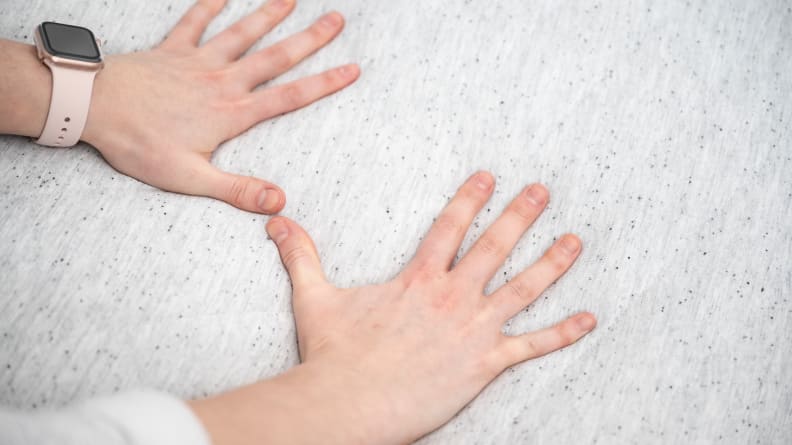 Pair of hands pressing down on a mattress