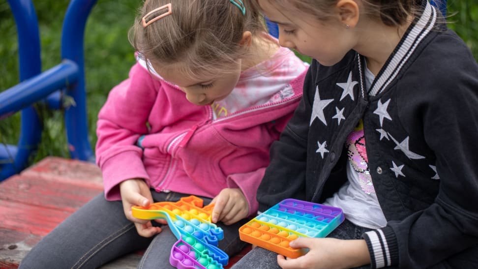 Two girls play with colorful Pop Its