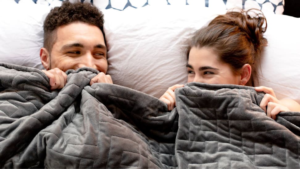 Couple giggling under a weighted blanket