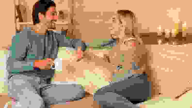 a woman and man talk with tea on the couch