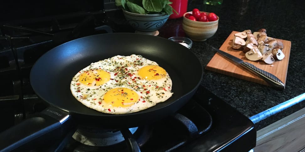 Three eggs frying in a nonstick skillet on a gas cooktop.