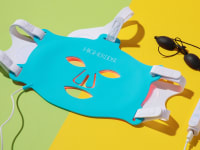 HigherDose Red Light Face Mask next to black eye goggles.