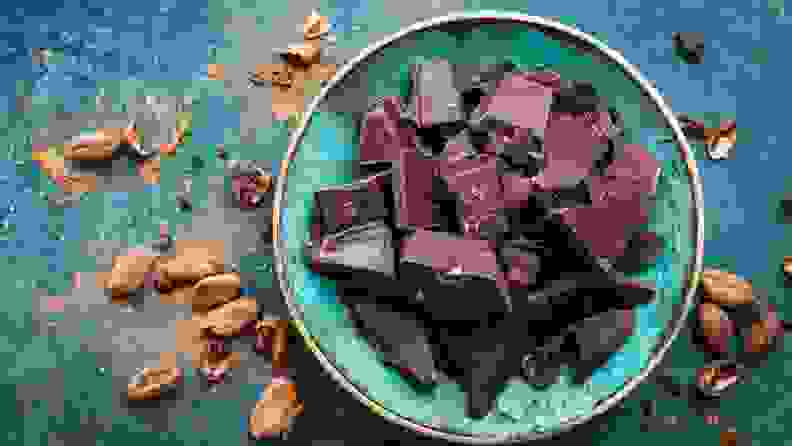 a bowl of dark chocolate surrounded in powder and on a teal background