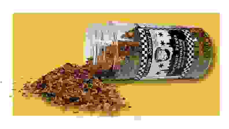 Open spice container spilling over on a yellow background
