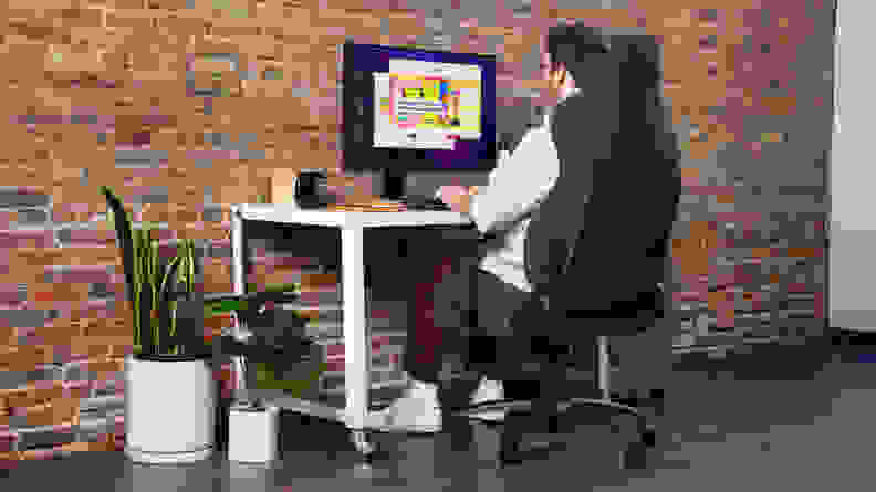 A person sitting on the gaming chair and interacting with a desktop.