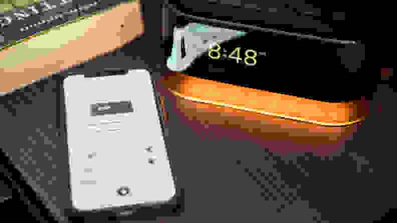 the loftie alarm next to a phone with the alarm app open