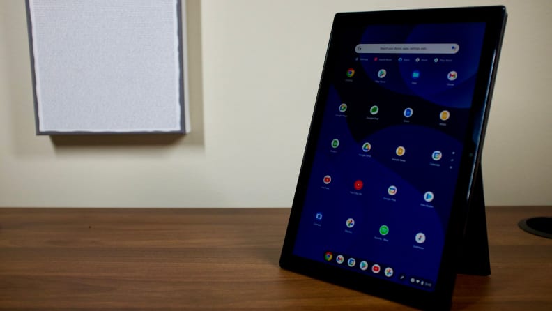 The Chromebook Detachable CM3 in portrait mode, being held up by its kickstand. The ChromeOS app drawer is on-screen, showing a variety of Google apps, including Chrome, Docs, and the Play Store.