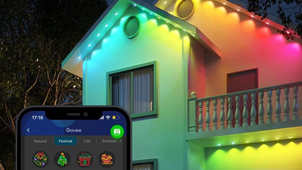 A house lit up by Govee lights and a phone displaying the Govee app.
