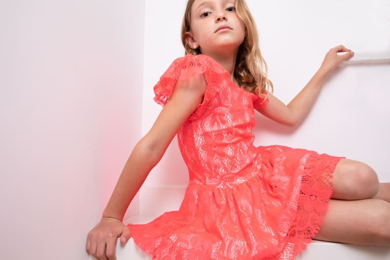 A girl wearing a bright pink lace dress.