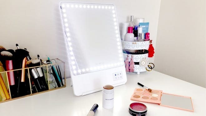 The Glamcor Riki Skinny Makeup Mirror on a white desk.