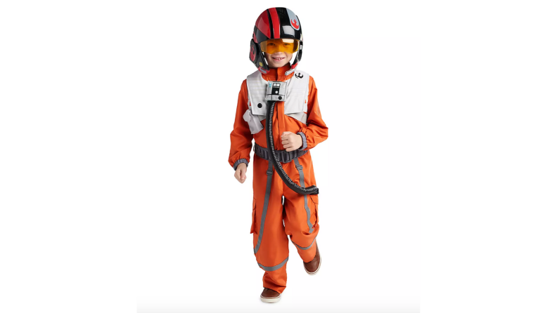 A young child wearing an orange flight suit costume.