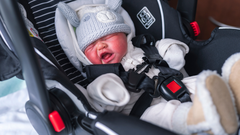 A newborn sits in a car seat