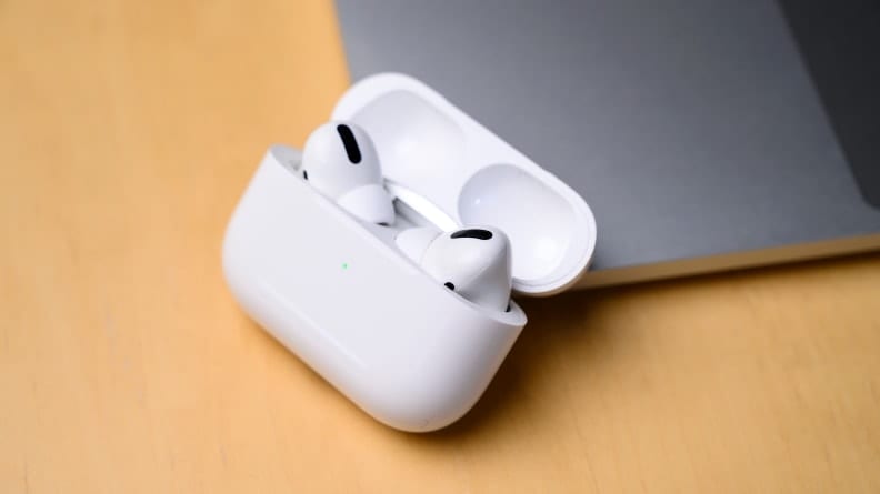 A pair of AirPods Pro, in their case, resting against a wooden surface.