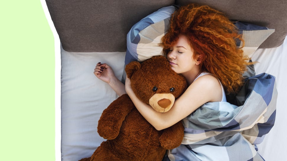 Woman sleeping in bed with brown teddy bear