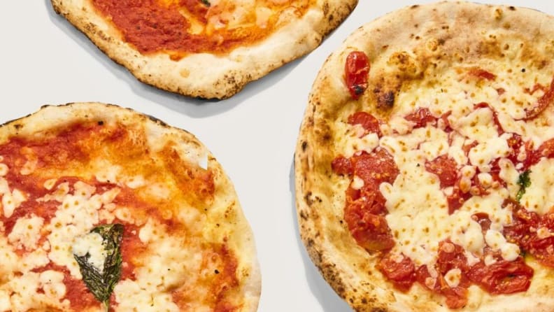 A top down photo of three pizzas against a white surface.